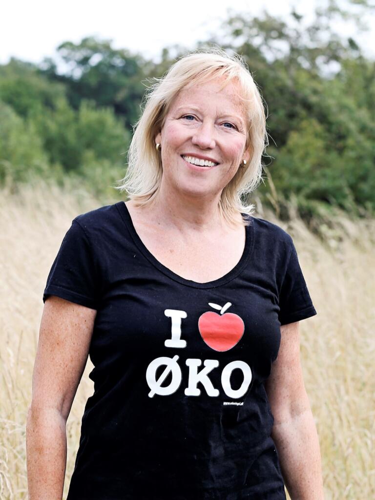 Birte Brorson står i naturen iført en t-shirt med teksten "I 🍎 Øko" hvor æblet er formet som et hjerte.